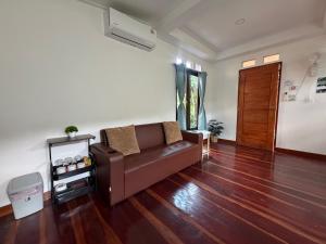 a living room with a couch and wooden floors at Baan Suan Sunset in Ban Laem Sai