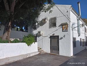 a white building with a door and a tree at Alojamiento Rural La Granja in La Cerradura
