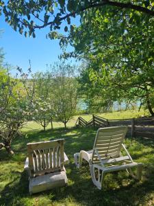 two rocking chairs and a bench in the grass at Cabane Layénie sous les étoiles in Bajamont