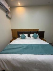 a bedroom with a large white bed with blue pillows at Hotel Kanta Kuteer Barsana in Barsāna