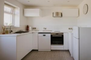 a white kitchen with white cabinets and a dishwasher at Coach House in Milton Keynes
