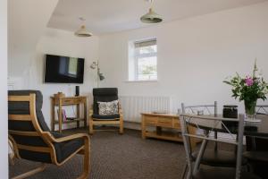 a living room with a table and chairs and a tv at Coach House in Milton Keynes