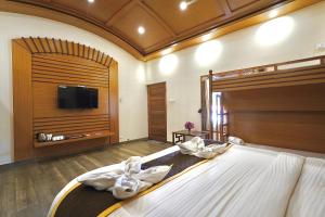 a bedroom with a large bed with a flat screen tv at Singaras Coffee Country in Masinagudi