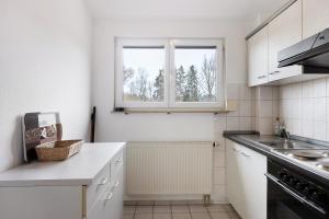 a white kitchen with a sink and two windows at Apartment 36 in Bad Dürrheim