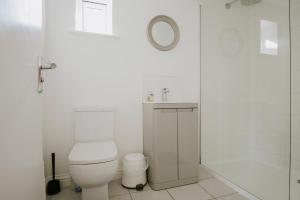 a white bathroom with a toilet and a shower at Coach House in Milton Keynes +36 photos