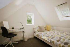 a bedroom with a bed and a desk and a window at Coach House in Milton Keynes