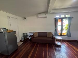 a living room with a couch and wooden floors at Baan Suan Sunset in Ban Laem Sai