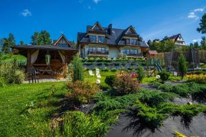 a large house with a garden in the yard at Tybet Domki i Apartamenty in Bukowina Tatrzańska