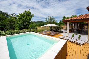 a swimming pool on a wooden deck with chairs and an umbrella at Agriturismo Rouna in Duino