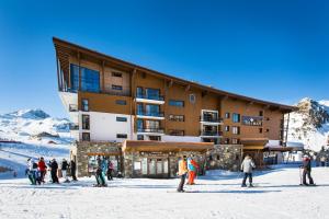 un grupo de personas de pie en la nieve frente a un edificio en Hôtel Taj-I Mah by Les Etincelles en Arc 2000