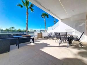 a patio with a table and chairs and palm trees at La Llana Beach MDC - 8010 in Mar de Cristal