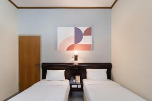 two beds in a room with white walls at Cove Rumah Asri in Bandung