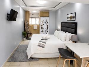 a bedroom with a large white bed and a table at Comfort e Casa Lodge Near OR Tambo Airport in Kempton Park