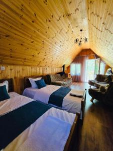 a bedroom with two beds in a wooden room at DEDULETI დედულეთი in Ambrolauri