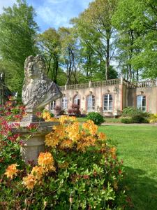 a statue in front of a house with flowers at Château de Montbrault in Fleurigné