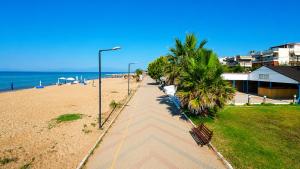 a sidewalk next to a beach with palm trees and a street light at Julia Country Home 200m from the Beach in Nea Plagia