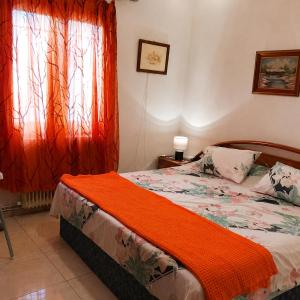 a bedroom with a bed with an orange blanket at Julia Country Home 200m from the Beach in Nea Plagia