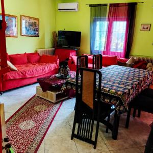 a living room with a table and a red couch at Julia Country Home 200m from the Beach in Nea Plagia