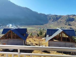 two houses with blue roofs on top of a hill at Peak Paradise homestay in Sainj