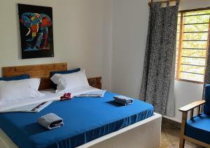 a bedroom with a bed with blue sheets and a window at Villa Rita in Gede