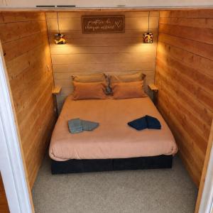 a bed in a small room with wooden walls at Tiny house cosy au cœur des bois in Arsac-en-Velay