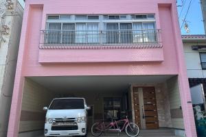 a truck parked in front of a pink house at Rabbit Island Inn in Mihara