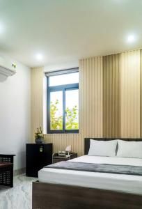 a bedroom with a large bed and a window at LUNA House in Can Tho