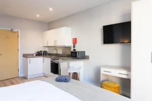 a room with a bed and a kitchen with a microwave at Spa Court in Cheltenham