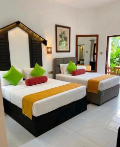 two beds in a hotel room with green and orange pillows at Sunshine Resort Sigiriya in Sigiriya