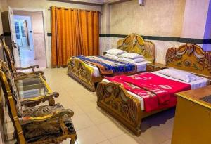 a hotel room with two beds and a chair at Redapple Rooms in Murree