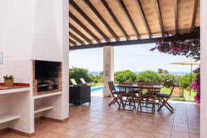 a patio with a table and chairs and a fireplace at Villa Ribes by Escape Home in Binibeca