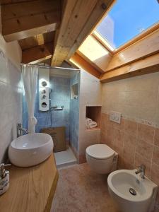 a bathroom with a sink and a toilet and a skylight at I LAGHEE casette BREVA e TIVANO Lakeside Garden Bike&Boat&Scooter Lake Como in Colico +42 photos