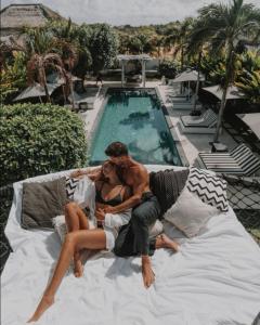 a man and a woman laying on a couch next to a pool at White Palm Uluwatu - Wellness & Recovery Retreat - 2 Min Walk to Balangan Beach in Jimbaran
