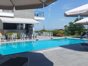 a swimming pool with chairs and umbrellas at Heraclea Luxury Suites in Nea Irakleia