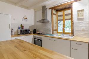 a kitchen with white cabinets and a sink and a window at Maison de campagne rénovée proche Argenton Sur creuse in Célon