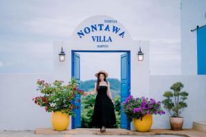 a woman in a black dress standing in front of a doorway at Nontawa Villa Doichang in Ban Huai Khai