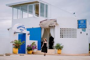 a woman in a black dress walking outside of a white building at Nontawa Villa Doichang in Ban Huai Khai