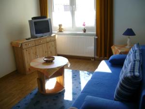 a living room with a blue couch and a tv at Ferienwohnung Nähe Dahme Flaeming-Skate in Rietdorf