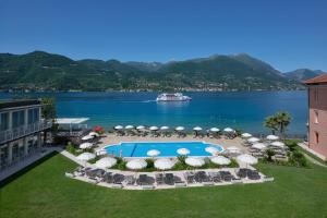 a resort with a swimming pool and a boat in the water at Park Hotel Casimiro in San Felice del Benaco