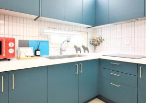 a kitchen with blue cabinets and a sink at From H Dongbaek Hotel by Kwon Gohyeon in Geoje