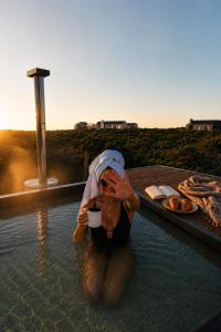a woman sitting in the water with a towel over her head at 401 Kingfisher in Gansbaai