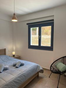 a bedroom with a bed and a chair and a window at Aegean Mirror Andros in Apróvaton