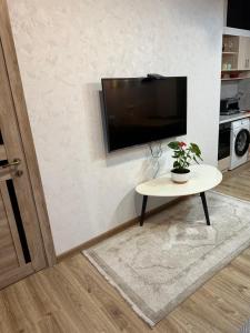 a living room with a table and a flat screen tv at Apartnuca in Batumi