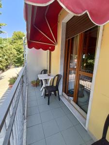 a balcony with a table and chairs and an umbrella at Maurin in Carrara