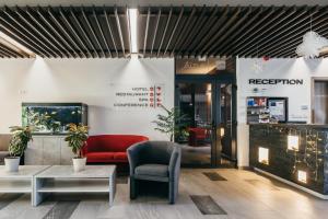 a lobby with a red couch and a chair at Altus Hotel & Spa in Praid +81 photos