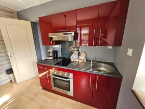 a kitchen with red cabinets and a sink at Superbe appartement 2 a 6 pers. hyper cocooning in Gérardmer