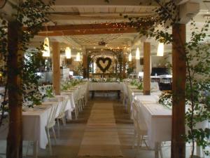 a long dining room with white tables and chairs at Brunnsta Gård in Bålsta