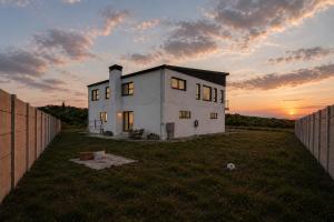 a white house in a field with the sunset in the background at Sea Mist Villa in Pearly Beach