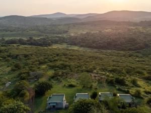 an aerial view of a house in a field with mountains at Sunset Safari Camp at Hluhluwe Game Park in KwaNompondo +13 photos