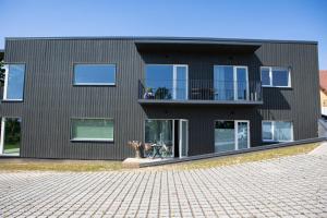 a black house with a balcony on a brick driveway at Järvevaatega studio apartment in Viljandi